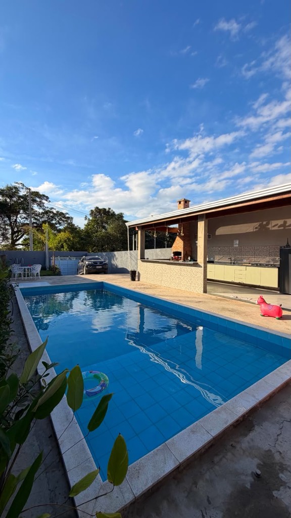 Piscina externa com churrasqueira ao fundo no Espaço Canto dos Pássaros em Sorocaba