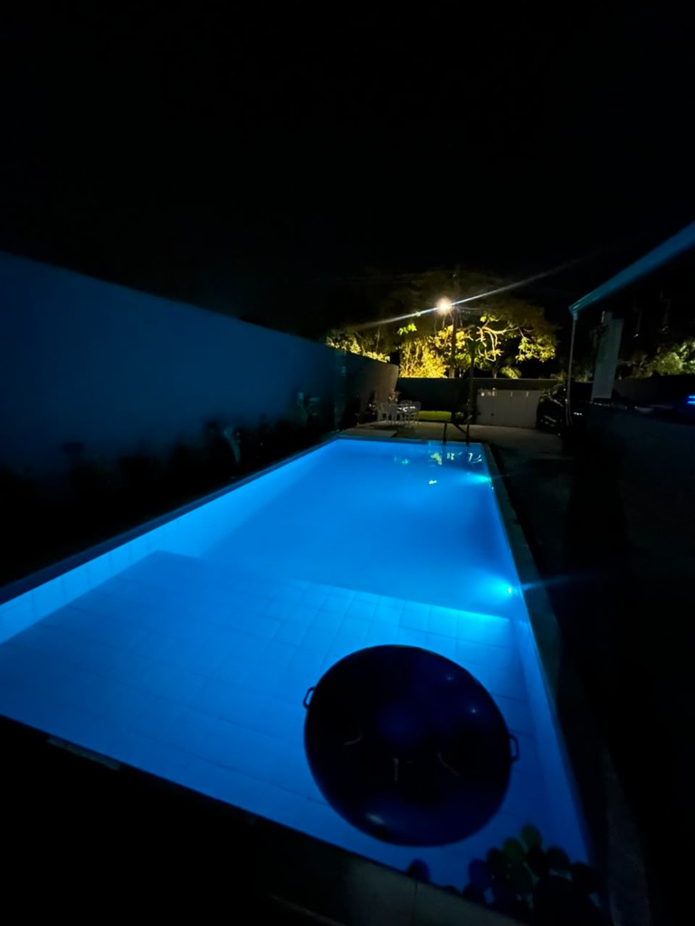 Piscina iluminada em azul à noite na chácara para eventos